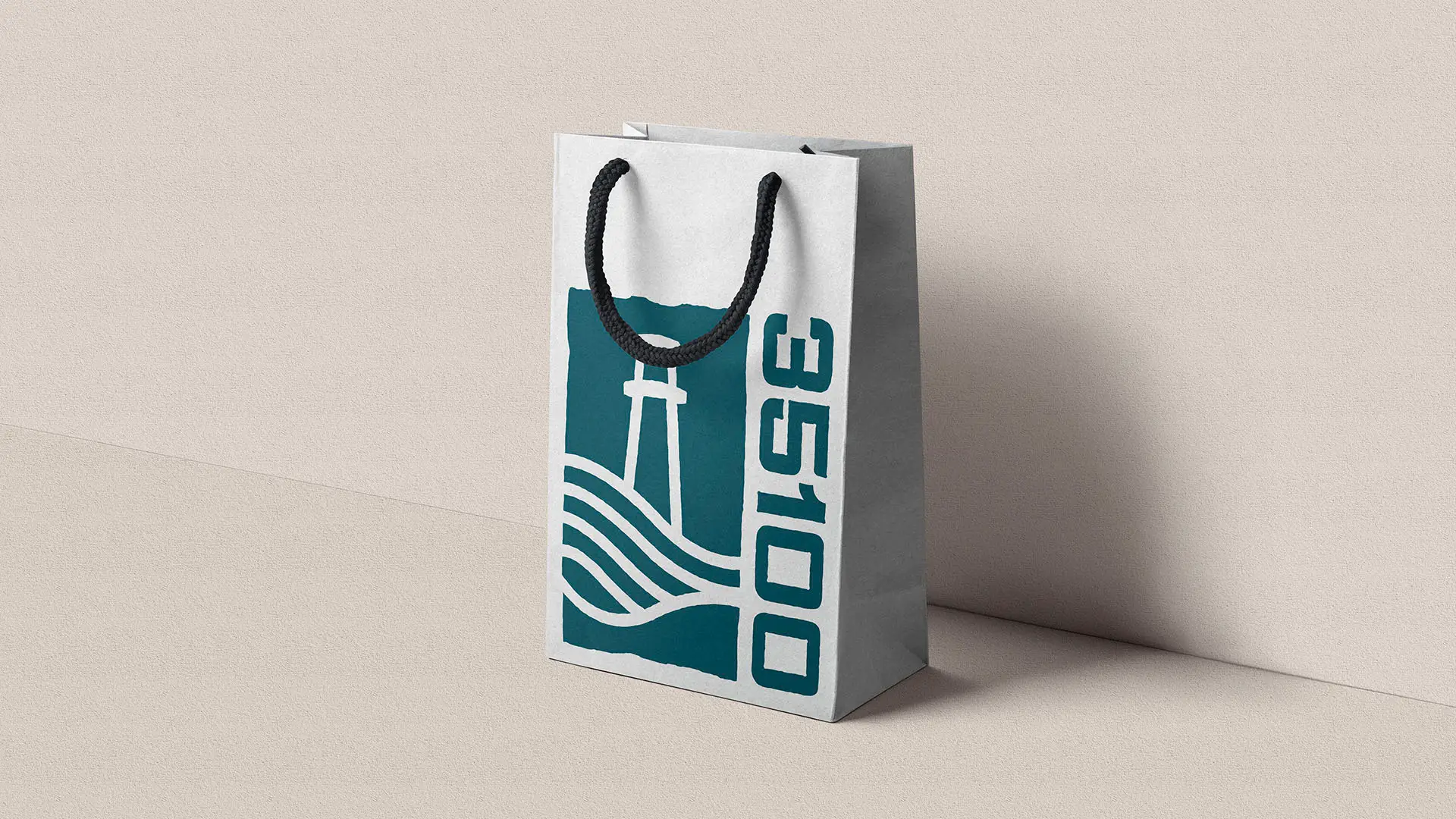 White paper shopping bag with a teal logo featuring a tower, waves, and the text 35100