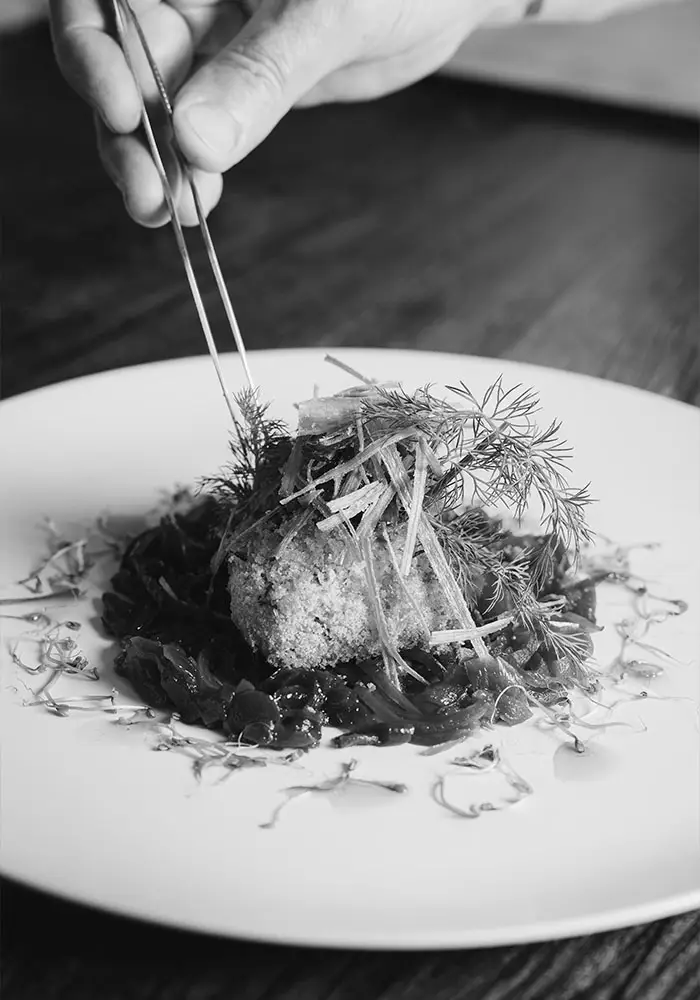 Chef emplatando un plato de alta cocina con pinzas
