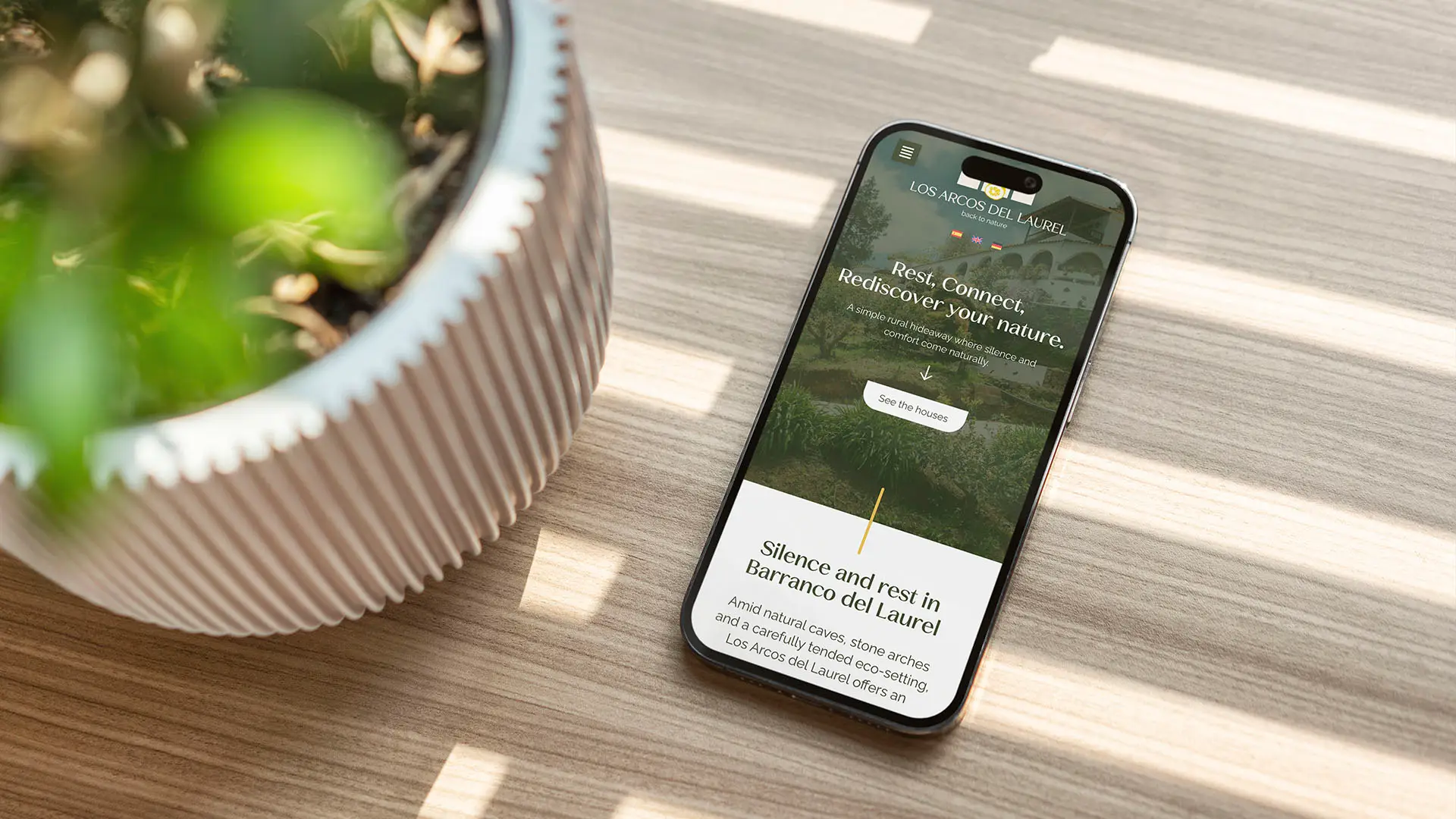 Mobile phone displaying the Los Arcos del Laurel website with the headline "Rest, Connect, Rediscover your nature